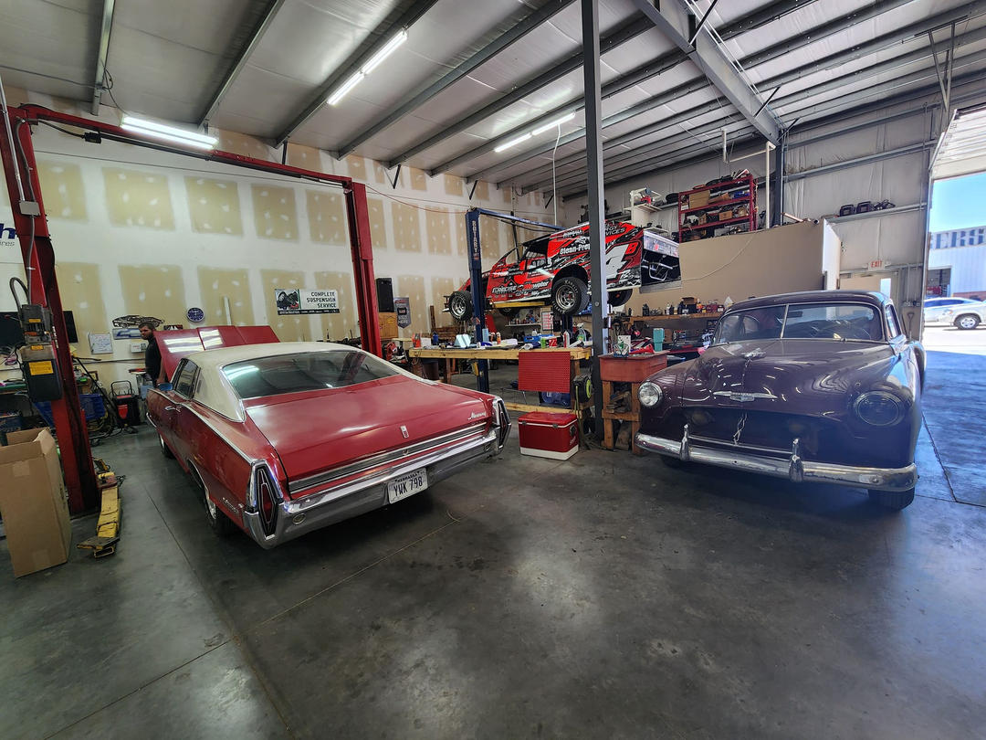 classic cars in the shop with race car up on the lift